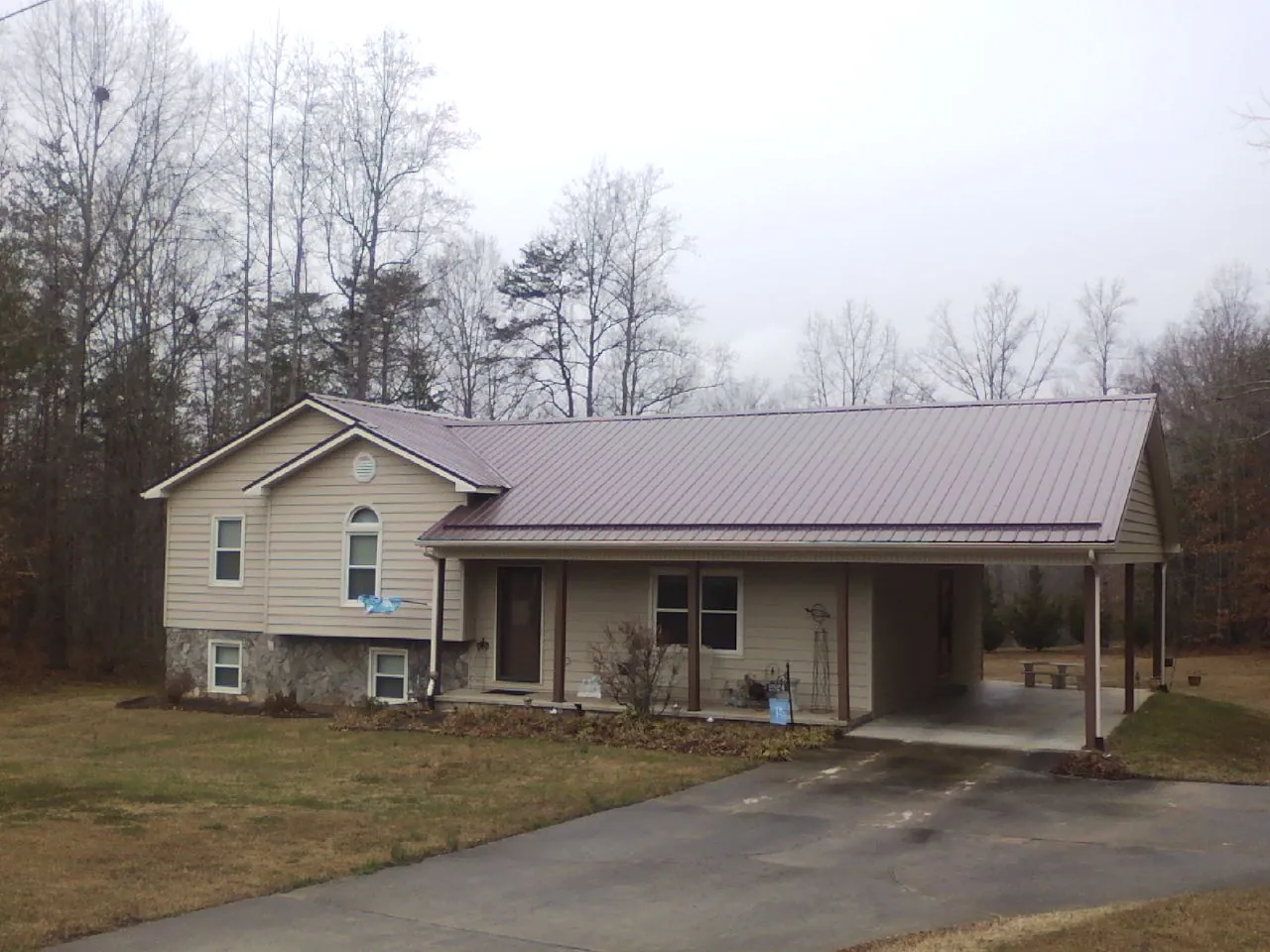 Burgundy metal roof on a tan split level home with an attached carport in De Beque