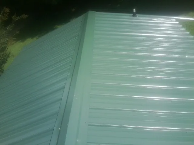 New green metal panels meeting at the ridge of a roof — Flat Roof Repair work by our crew in De Beque
