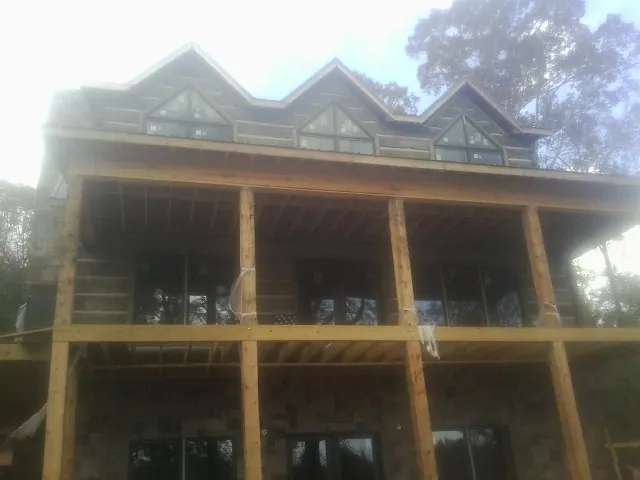 Dormers and porch framing on a large log home under construction — Roof Coating work by our crew in De Beque