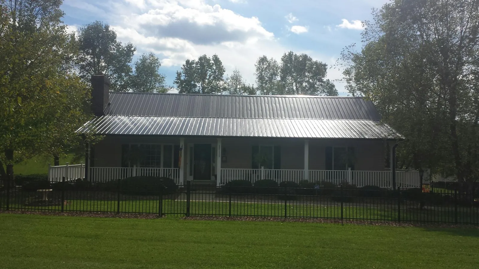 Gray metal roof on a brick ranch with a full width front porch — Gutter Guard Installation work by our crew in De Beque