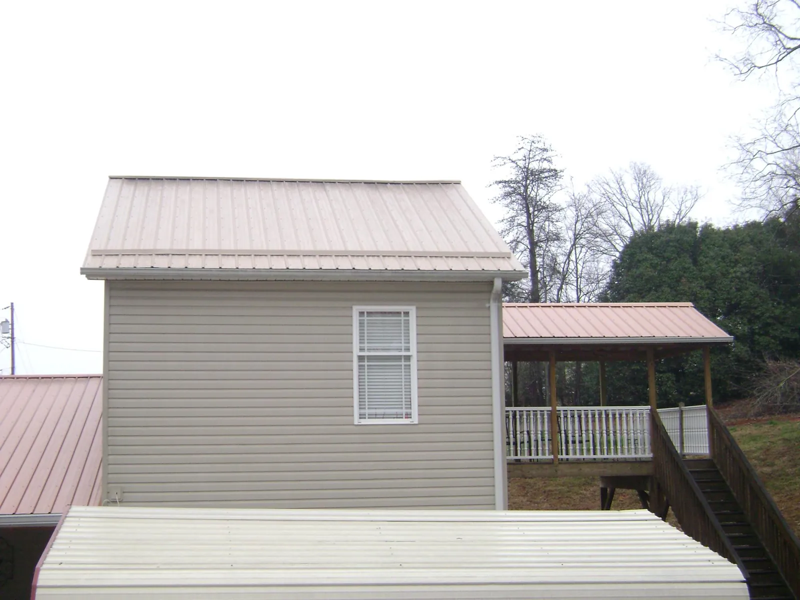 Tan metal roofs on a two story addition and attached porch, from a Roof Replacement job in De Beque